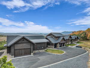 View of front facade featuring stone siding, a mountain view, asphalt driveway, and a garage