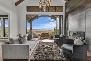 Living area with a mountain view, lofted ceiling, wood finished floors, a tile fireplace, and suspended lighting