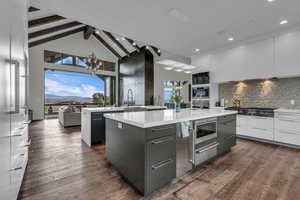 Kitchen with dark wood-style flooring, modern cabinets, a warming drawer, light stone counters, and two tone cabinets