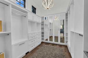 Walk in closet featuring a chandelier and dark wood finished floors