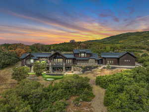 Back of house featuring a chimney, a metal roof, a balcony, and stone siding