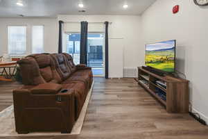 Living room featuring light wood finished floors, healthy amount of natural light, and recessed lighting