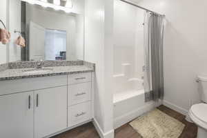 Full bathroom featuring shower / tub combo with curtain, vanity, and dark wood finished floors