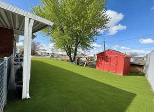 Fenced backyard with a storage unit and a playground