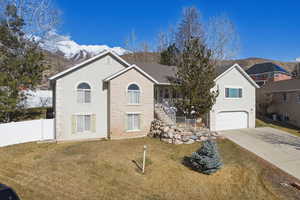 View of front of house with a mountain view, a front yard, an attached garage, concrete driveway, and brick siding