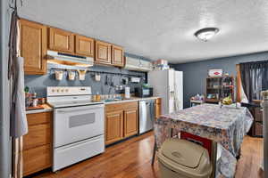 Kitchen featuring dark wood-style floors, white appliances, light countertops, and a textured ceiling