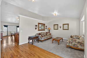 Living area featuring plenty of natural light, wood-type flooring, and vaulted ceiling