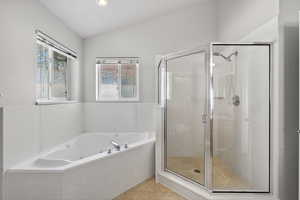 Bathroom with lofted ceiling, a shower stall, light tile patterned floors, and a whirlpool tub