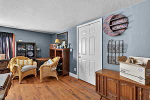 Living area with a textured wall, a textured ceiling, and hardwood / wood-style flooring