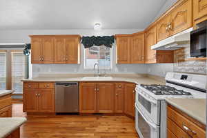 Kitchen featuring range with two ovens, stainless steel dishwasher, and light countertops