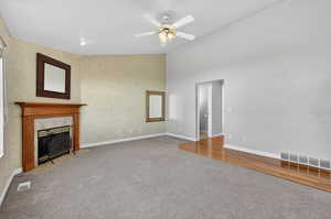 Unfurnished living room with light carpet, a tile fireplace, ceiling fan, and wallpapered walls
