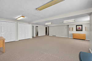 Huge Basement Family room with light colored carpet and a textured ceiling with Daylight windows and entrance