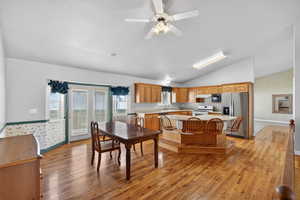 Dining space featuring a ceiling fan, light wood finished floors, lofted ceiling, and wallpapered walls