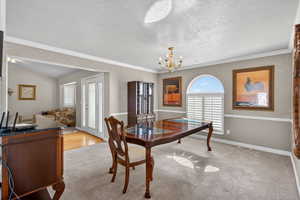 Formal Dining space featuring light carpet, hanging lights, a textured ceiling, and crown molding