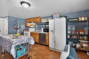 Kitchen featuring white appliances, dark wood finished floors, light countertops, a textured ceiling, and wood finish cabinetry