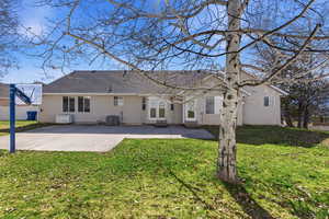 Rear view of property with a lawn, stucco siding, roof with shingles, a patio, and entry steps