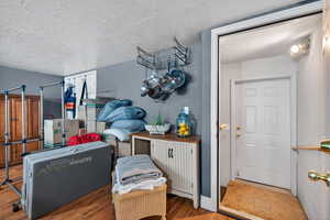 Interior space with light wood-type flooring, a textured ceiling, and a textured wall