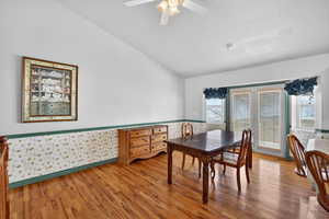 Dining room with wallpapered walls, lofted ceiling, light wood finished floors, and a ceiling fan