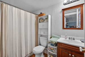 Full bath in ADU with a textured wall, vanity, a shower with curtain, a textured ceiling, and dark wood-type flooring