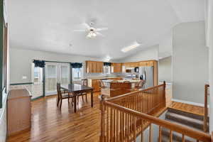 Kitchen with light wood-style flooring, light countertops, ceiling fan, a center island, and stainless steel refrigerator with ice dispenser