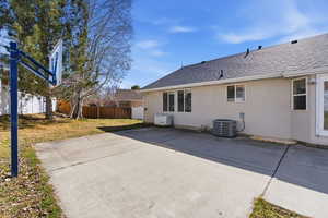 Rear view of house featuring a shingled roof, a fenced backyard, a patio, and stucco siding