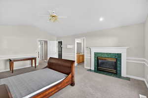 Master bedroom featuring lofted ceiling, a ceiling fan, a fireplace, and connected bathroom