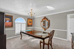 Formal Dining area featuring light carpet, suspended lighting, a textured ceiling, and crown molding