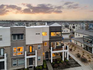 View of front of property with a balcony, brick siding, stucco siding, and a residential view