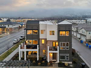 View of front of property with stucco siding, a balcony, and brick siding