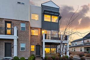 Contemporary house with a balcony, brick siding, and stucco siding