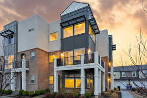 View of front of home featuring brick siding, stucco siding, and a balcony