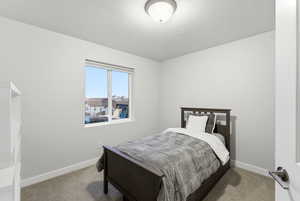 Bedroom with light colored carpet and a textured ceiling