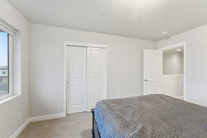 Bedroom with light carpet, a closet, and a textured ceiling