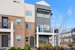 Modern home featuring a balcony, brick siding, and stucco siding