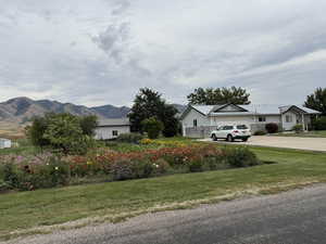 View of green lawn with driveway, a garage, and a mountain view