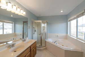 Full bathroom featuring a tub with jets, healthy amount of natural light, double vanity, a shower stall, and recessed lighting