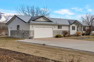 Ranch-style home with a garage, concrete driveway, a metal roof