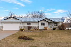 Ranch-style home featuring mountain view, garage, front yard, and concrete driveway