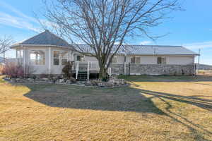 View of back of home with a metal roof, a deck, and sunroom