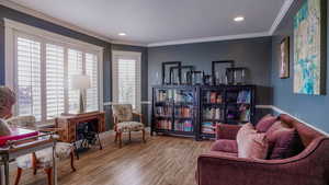 Sitting room with wood finished floors, recessed lighting, and ornamental molding