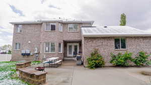 Back of house with an outdoor fire pit, a patio, and brick siding