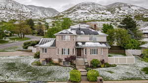 View of front of house featuring solar panels, a mountain view, brick siding, and a chimney