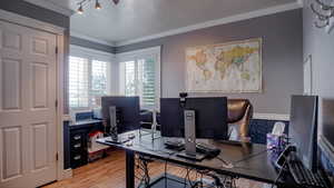 Bedroom or Office featuring light wood finished floors, ornamental molding, and a textured ceiling