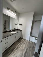 Bathroom with vanity, light wood-style floors, shower / bath combination, and a textured ceiling