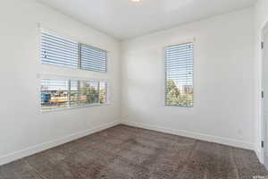 Unfurnished room featuring dark colored carpet and plenty of natural light