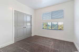 Unfurnished bedroom featuring dark colored carpet and a closet
