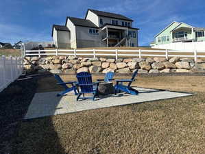 Fenced backyard featuring a fire pit, a patio area, and a residential view