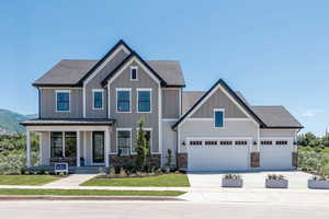 View of front of home with a porch, board and batten siding. and 5 car garage.
