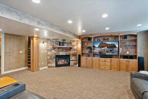 Carpeted living room with recessed lighting and a stone fireplace