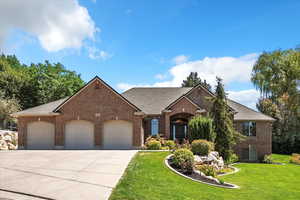 View of front of house with an attached garage, brick siding, a front lawn, and roof with shingles